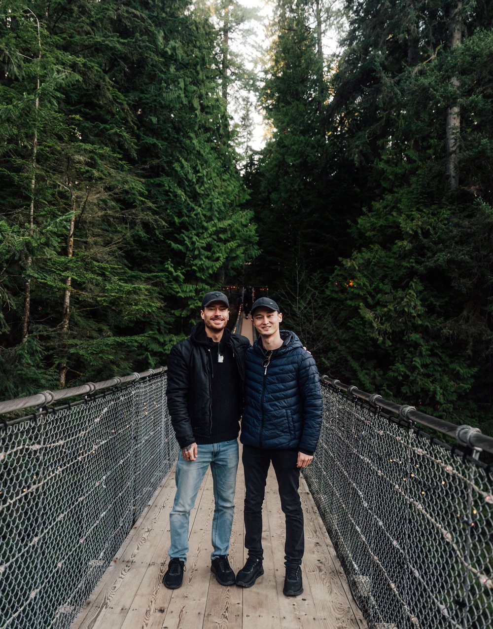 Bronsen and Caleb on a suspension bridge among tall evergreens