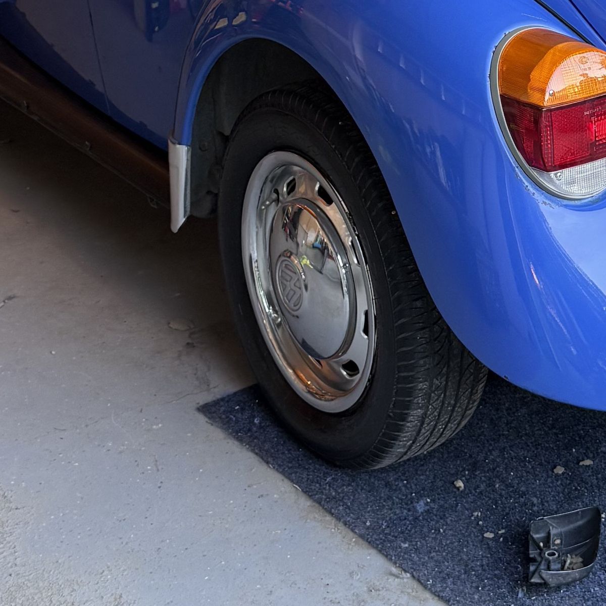 Polished original hubcap on the rear wheel, blue fender curving above