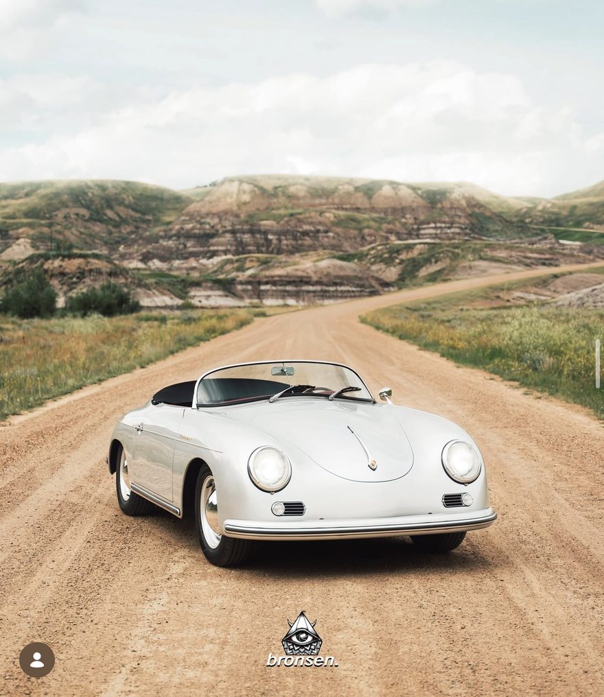 A silver Porsche 356 Speedster on a dirt road through the badlands