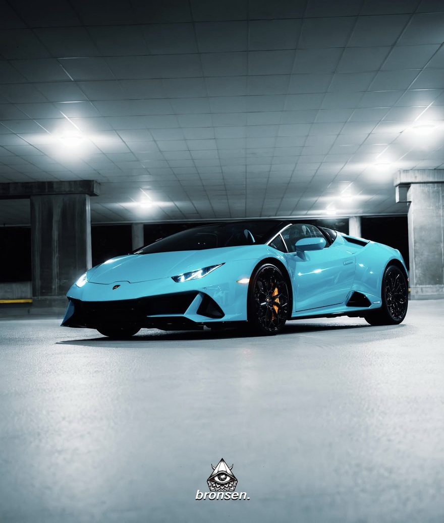 A pale blue Lamborghini Huracán Spyder in a dim parkade at night
